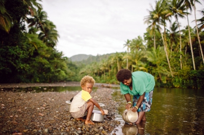 A woman cleans her pots in a river while her child watches. (Department of Foreign Affairs and Trade)  [flickr.com]  CC BY 
Infos zur Lizenz unter 'Bildquellennachweis'